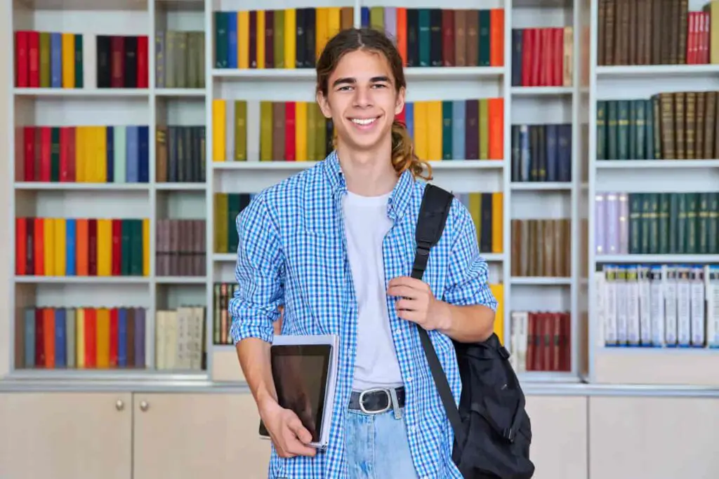 An image of a student teenager guy looking at camera in library.