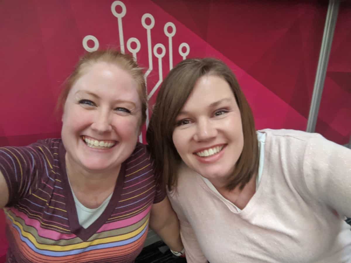 Kimberly and Breanne in front of a pink Roots Tech banner at the 2020 convention in Salt Lake City