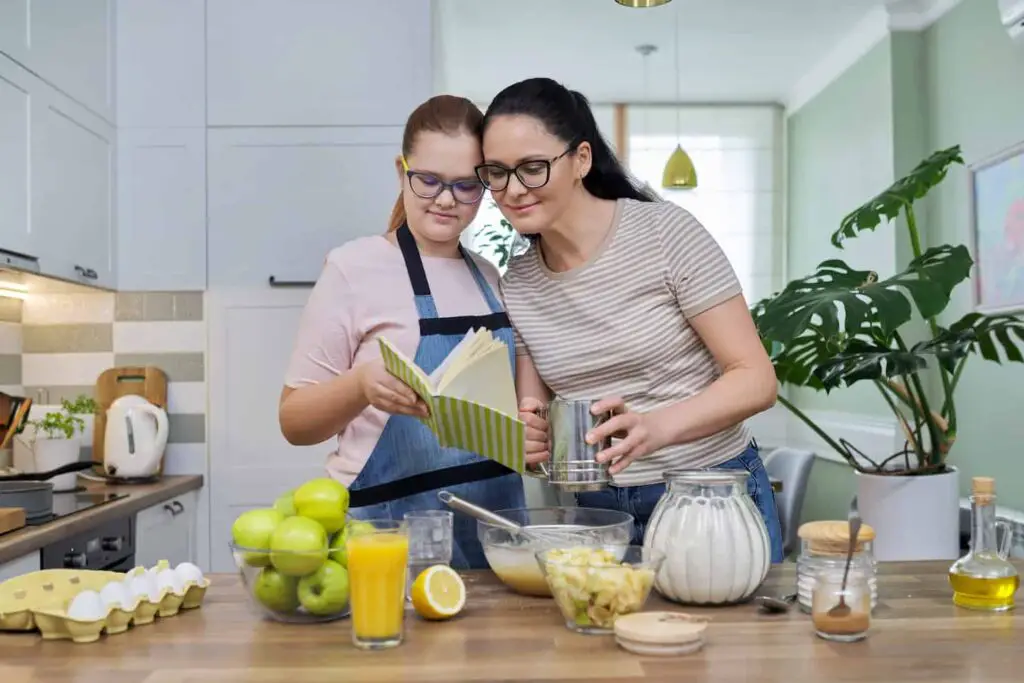 An image of a Mom and teenage daughter preparing apple pie in kitchen together.
