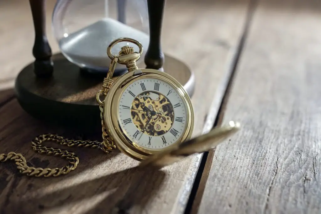 An image of a Vintage pocket watch and hour glass or sand timer, symbols of time with copy space.