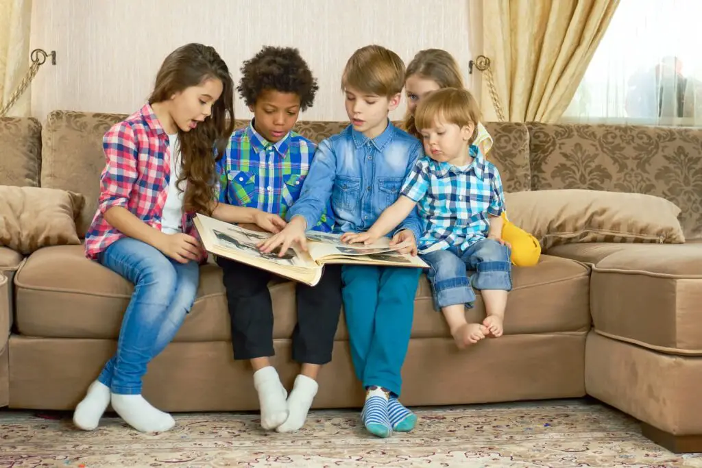 An image of kids in the living room looking through photo album.