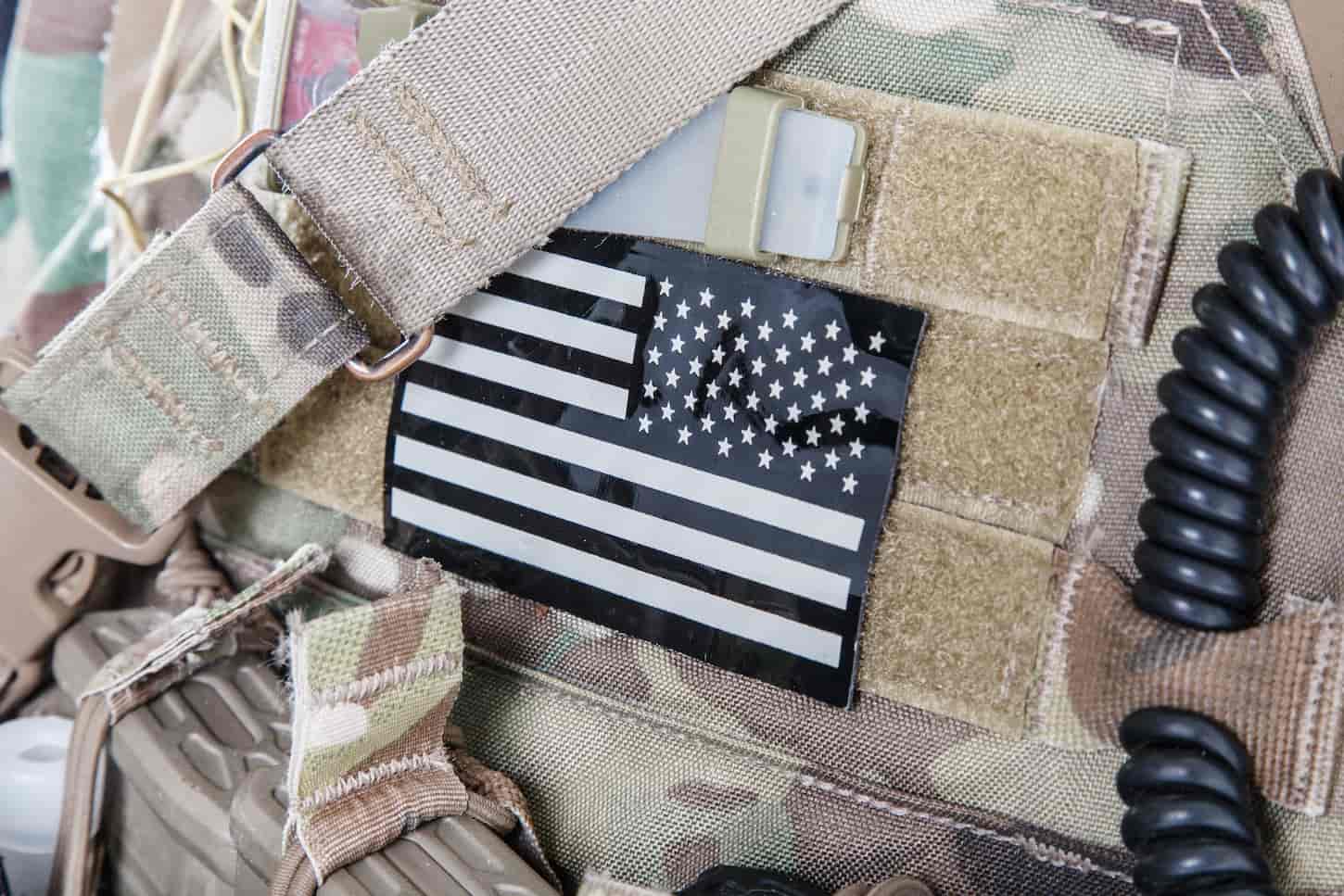 An image of the American flag stars stripes military patches on camouflage uniforms.