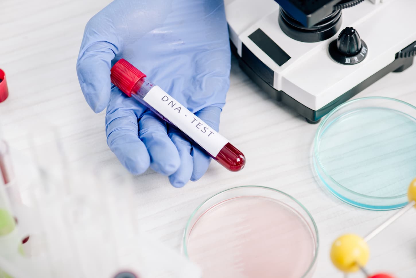 An image of a genetic consultant holding a test tube with DNA test lettering.