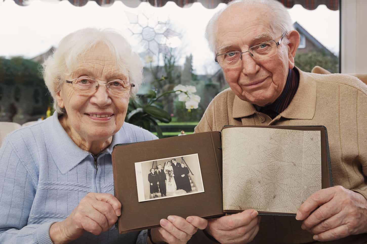 An image of a Senior couple showing an old photograph of the wedding day.