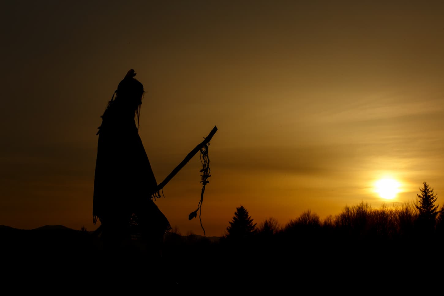 An image of a silhouette of a Native American shaman with pikestaff.