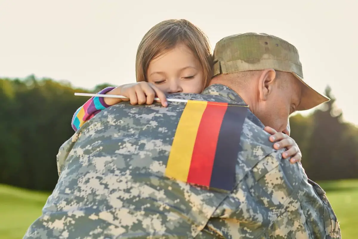 An image of a Little girl with a Deutsch flag hugging her father.