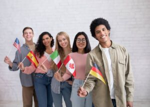 An image of a Modern education of international students or immigrants. Happy generation z multiracial people waving different countries flags at college classroom on white wall background.